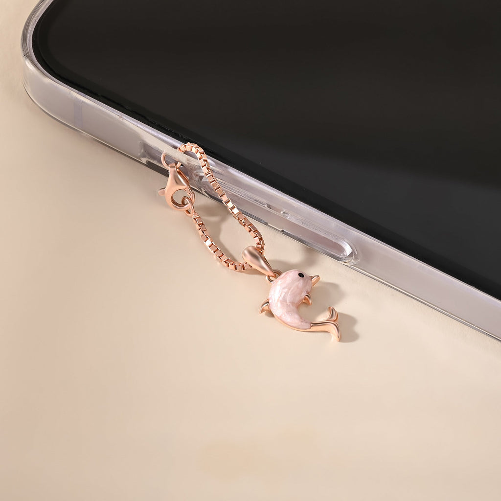 Rose gold dolphin charm on a phone case with a beige background